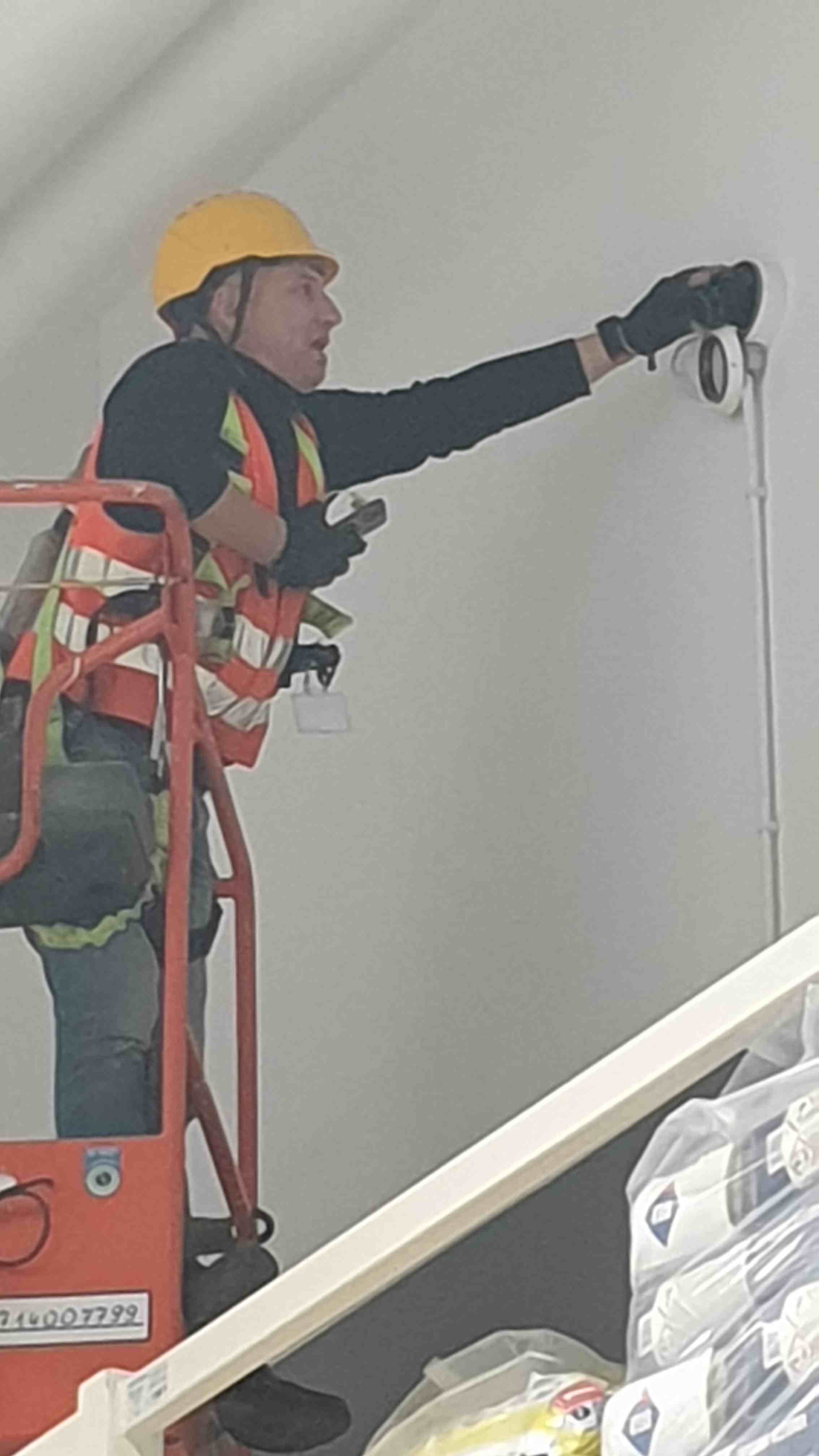 Technik na podnośniku montuje kamerę kopułkową – hala wielkopowierzchniowa