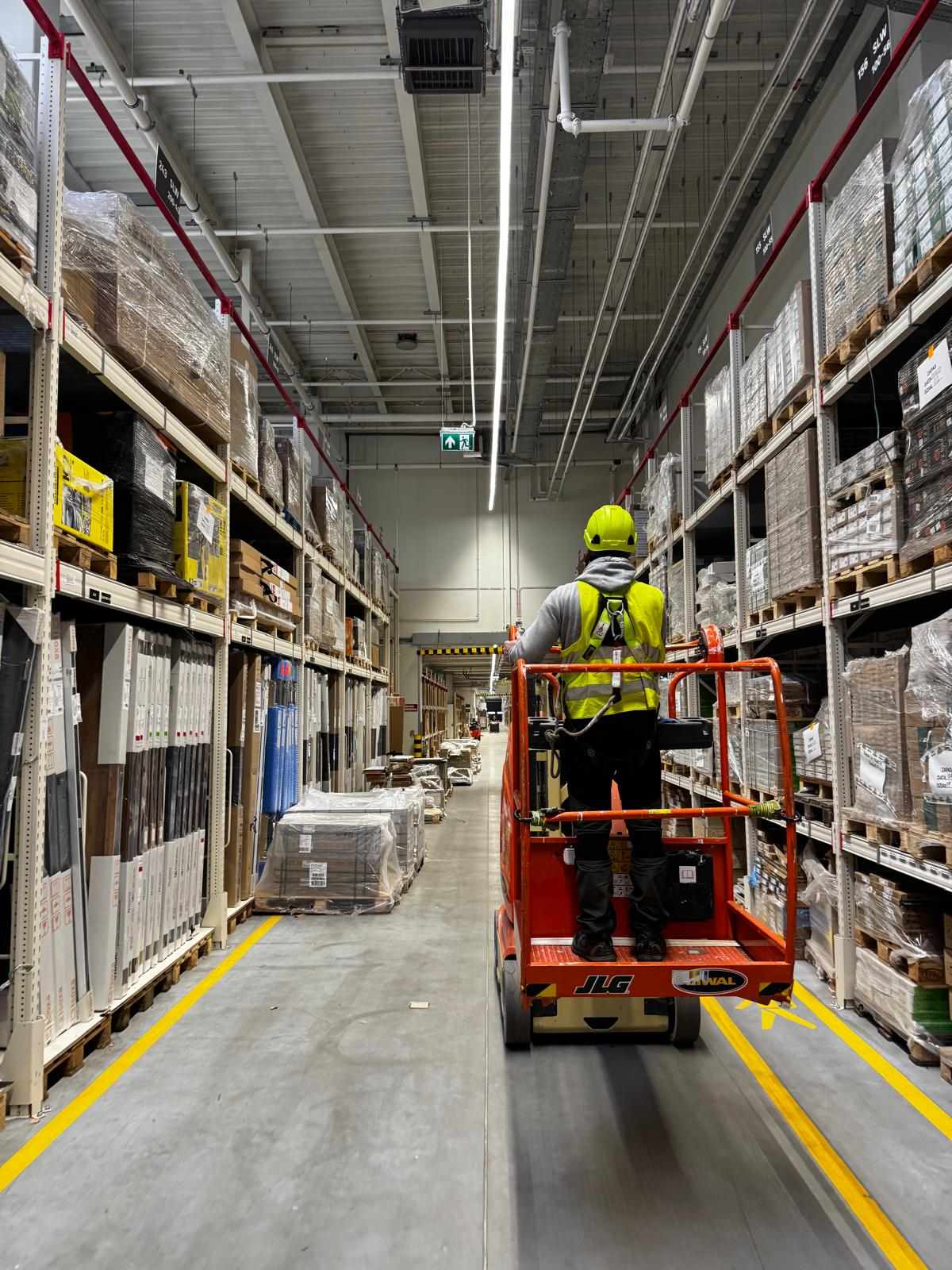 Technik na podnośniku JLG w hali magazynowej – instalacja kamer