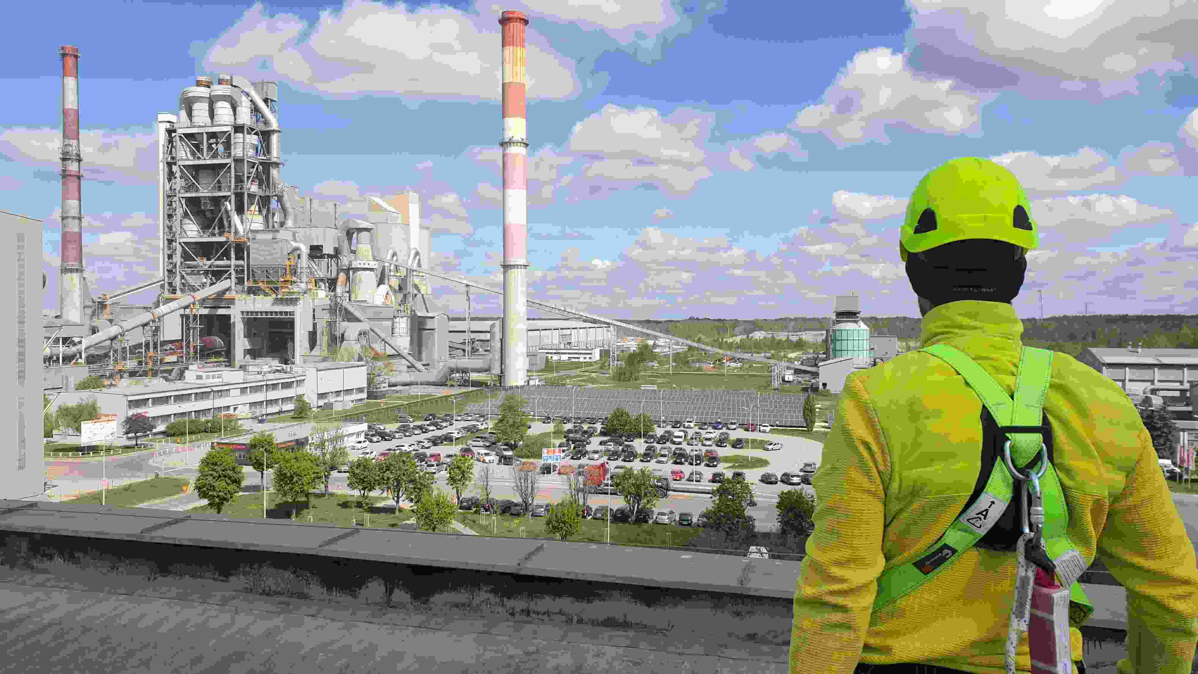 Widok z dachu cementowni – technik w żółtej kurtce, panorama zakładu